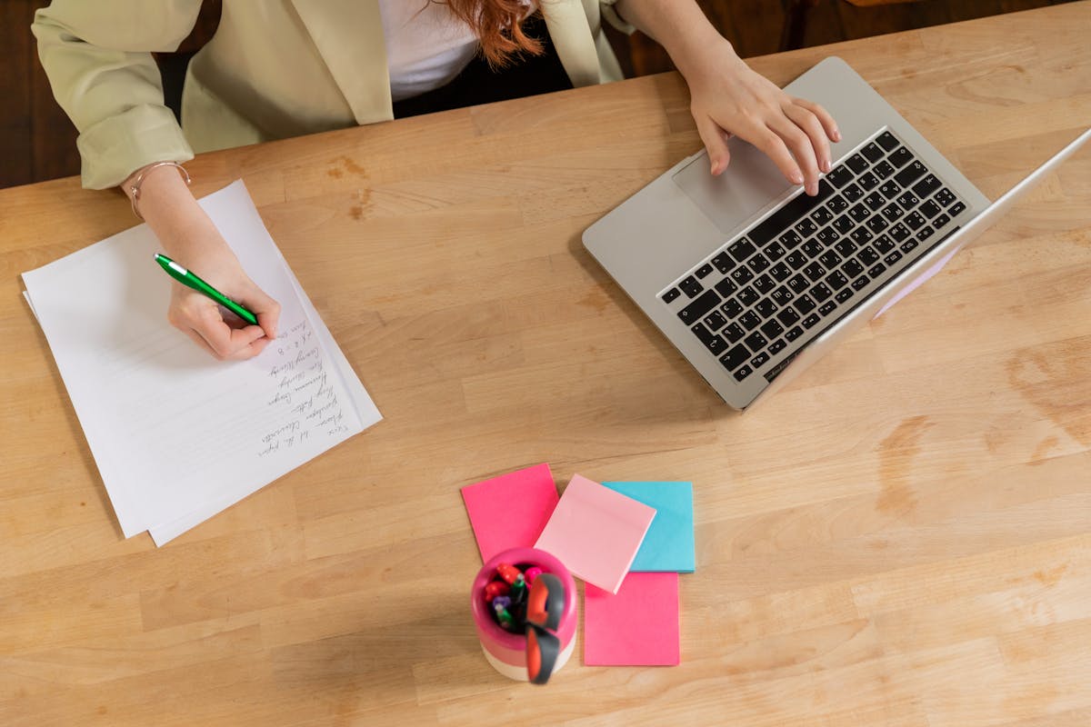 Iemand maakt aantekeningen terwijl een laptop open staat