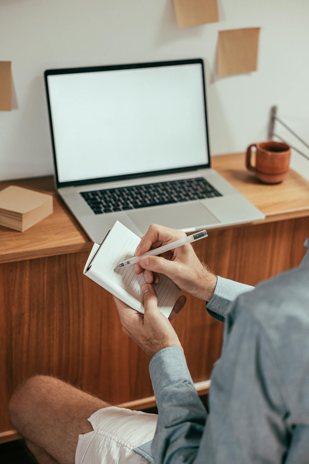Persoon maakt aantekeningen voor een laptop